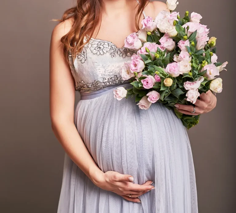 pregnant-woman-holds-hands-on-belly-with-flowers-2023-11-27-05-23-37-utc